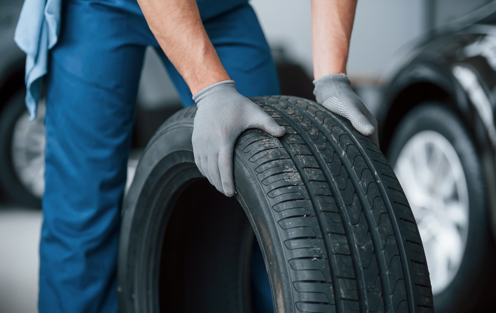 Mechanic in gloves holding a car tire in a service garage